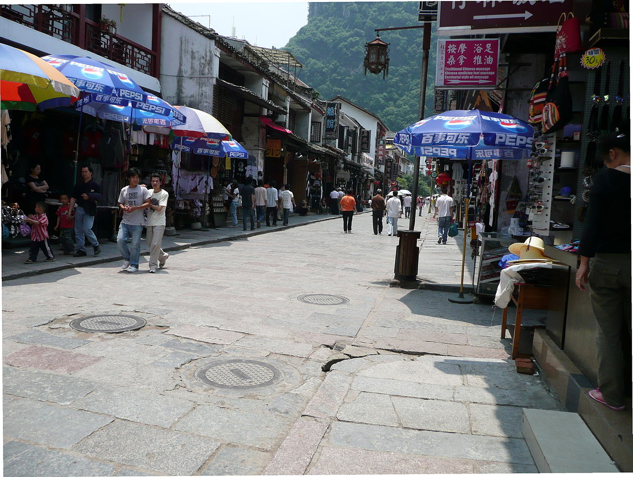 热闹的步行街，商店林立，背景是喀斯特山峰